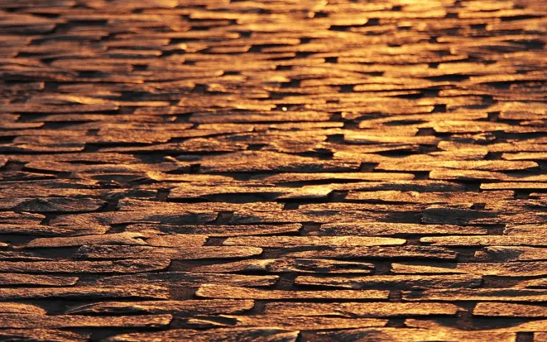 Vue en enfilade sur des pavés en pierre colorés en or par la lumière. Cela rappelle les couleurs d'automne des fils à broder DMC.