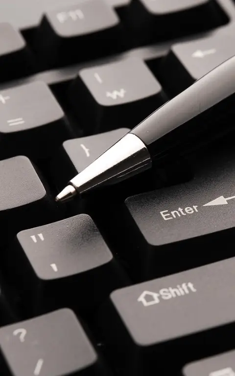 Contact moderne. Un stylo à bille noir avec l'embout couleur acier est posé sur un clavier d'ordinateur noir au niveau de la touche enter. La pointe du stylo est dirigée vers le bas à gauche.